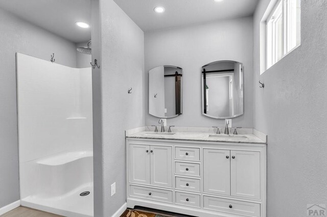 bathroom featuring double vanity, a sink, and a walk in shower