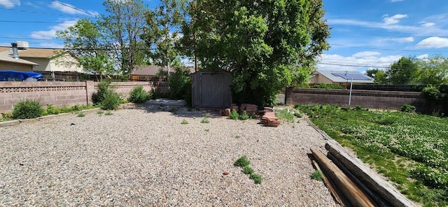 view of yard featuring a storage shed, fence, and an outbuilding