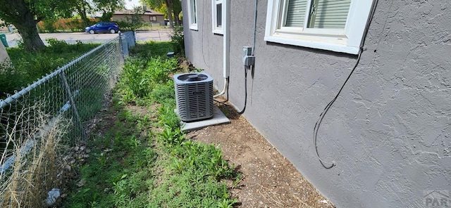 details with central AC unit, fence, and stucco siding