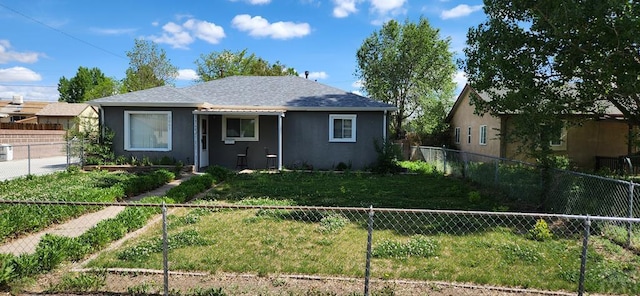 view of front of house with a front lawn, a shingled roof, fence private yard, and stucco siding