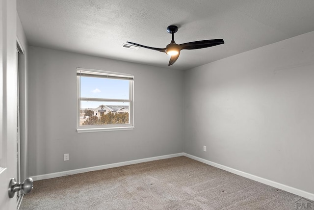 carpeted empty room featuring a ceiling fan, visible vents, a textured ceiling, and baseboards