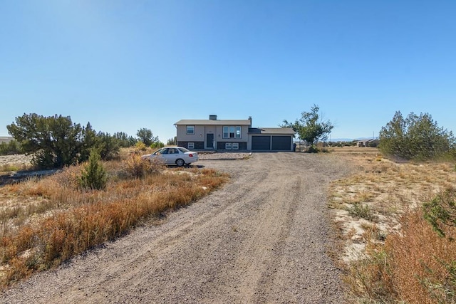 view of front of home featuring dirt driveway and a garage