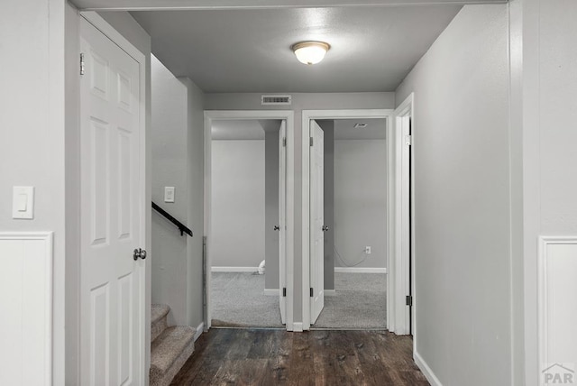 hallway with dark wood-style flooring, visible vents, and baseboards