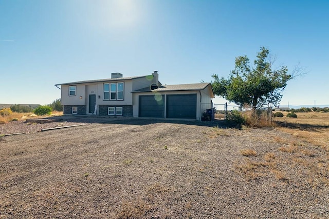 view of front of property featuring driveway, an attached garage, and fence