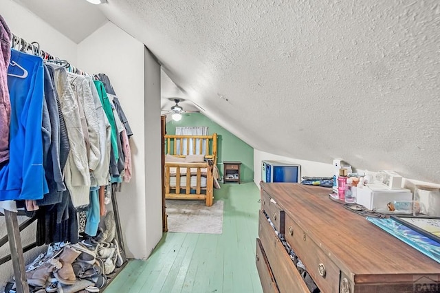 additional living space with light wood finished floors, vaulted ceiling, and a textured ceiling