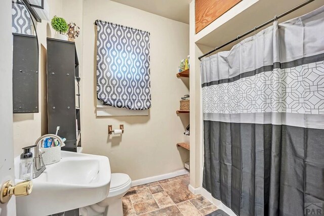 full bath featuring stone finish flooring, a sink, toilet, and baseboards