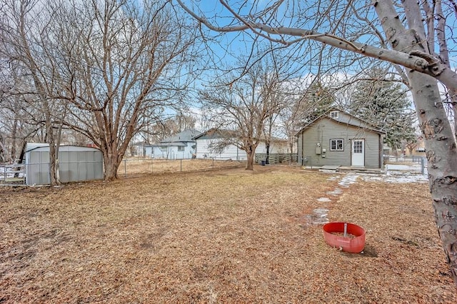 view of yard with a shed, fence, and an outbuilding