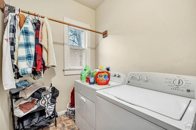 washroom with baseboards, laundry area, stone finish flooring, and washer and dryer