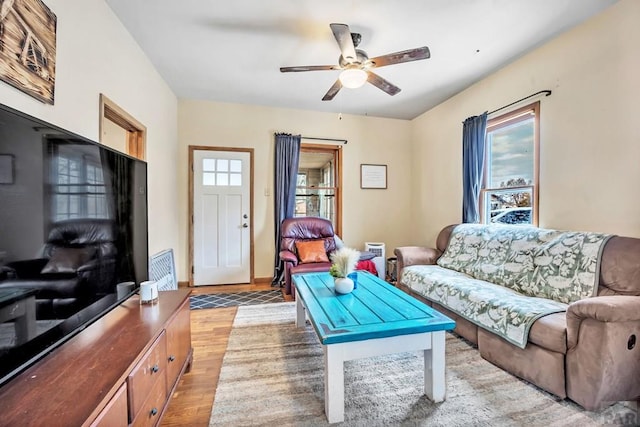 living room featuring baseboards, light wood-style flooring, and a ceiling fan