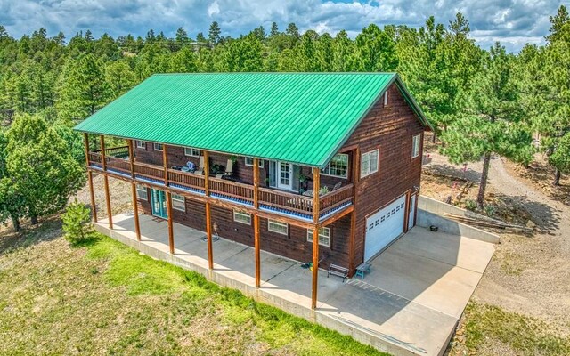 back of property with a garage, a patio area, driveway, and a wooded view