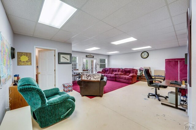 living area with french doors, concrete floors, and a drop ceiling