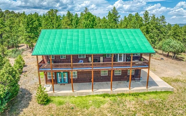 rear view of property with metal roof, a patio, and a wooden deck