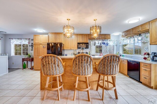 kitchen featuring pendant lighting, light countertops, black appliances, and light tile patterned floors