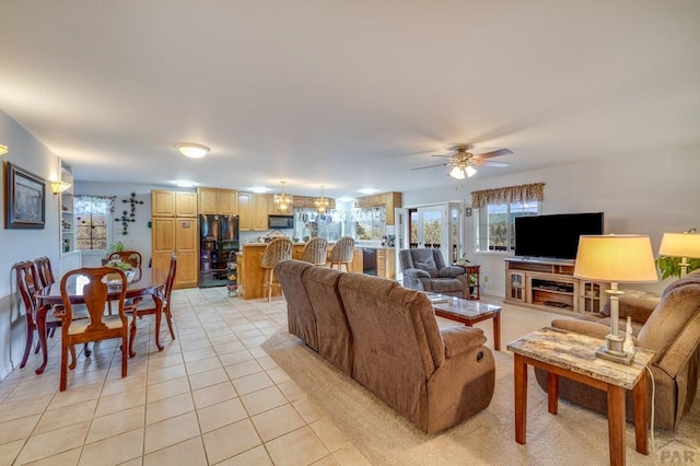 living area featuring light tile patterned floors and ceiling fan with notable chandelier