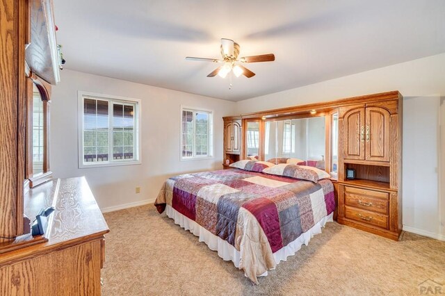 bedroom with a ceiling fan, light colored carpet, and baseboards