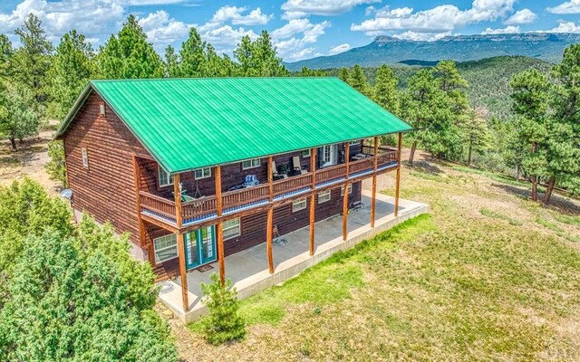 rear view of house featuring a deck with mountain view, a yard, metal roof, and a patio