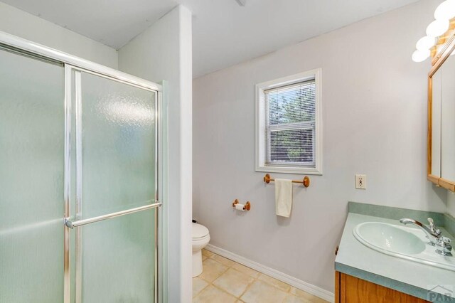 bathroom with baseboards, toilet, a shower with shower door, tile patterned floors, and vanity