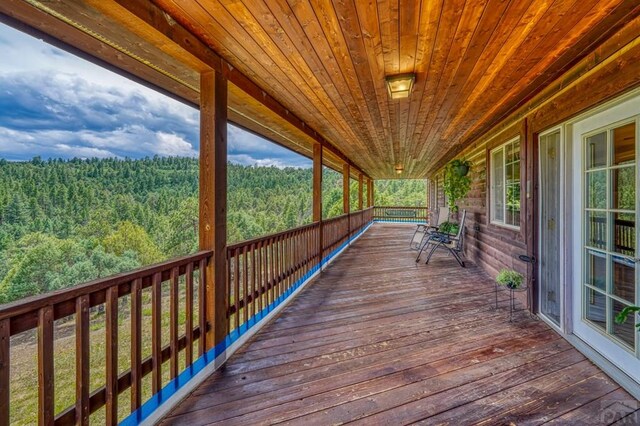 wooden terrace featuring a wooded view