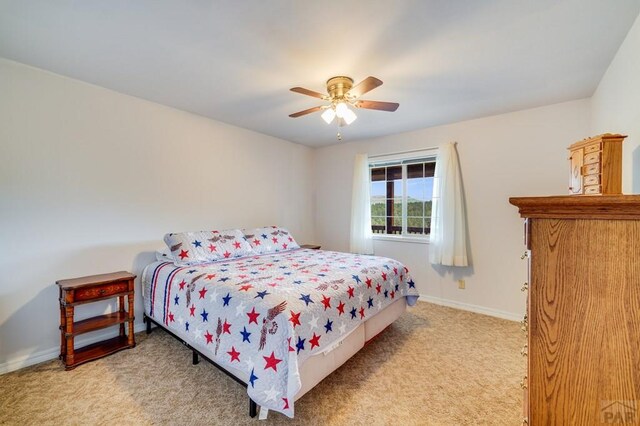 bedroom featuring light carpet, a ceiling fan, and baseboards