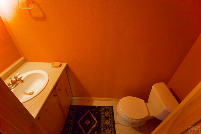 bathroom featuring vanity, tile patterned flooring, a textured wall, and toilet