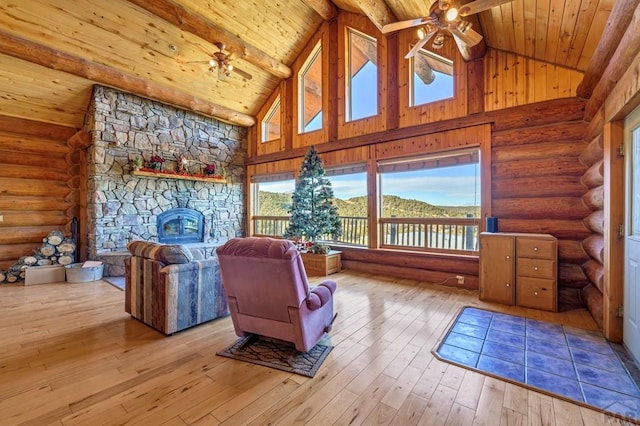 living area featuring a mountain view, light wood finished floors, wooden ceiling, and a ceiling fan