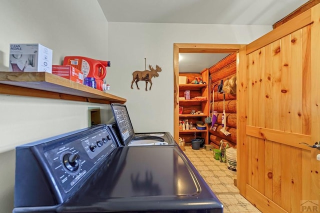 washroom featuring laundry area, rustic walls, washer and clothes dryer, and light floors