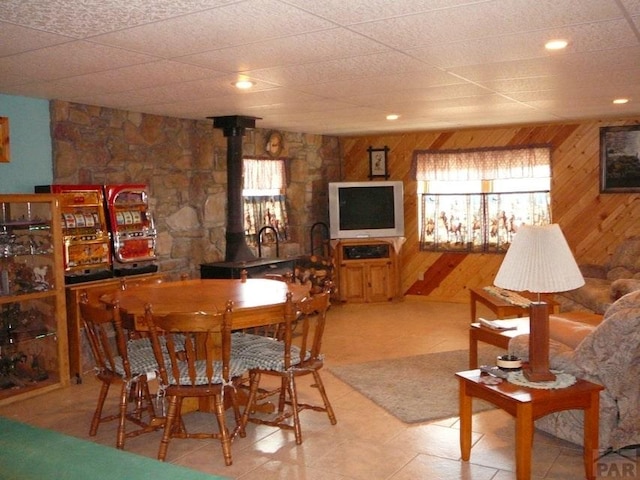 dining space featuring a wood stove and wooden walls