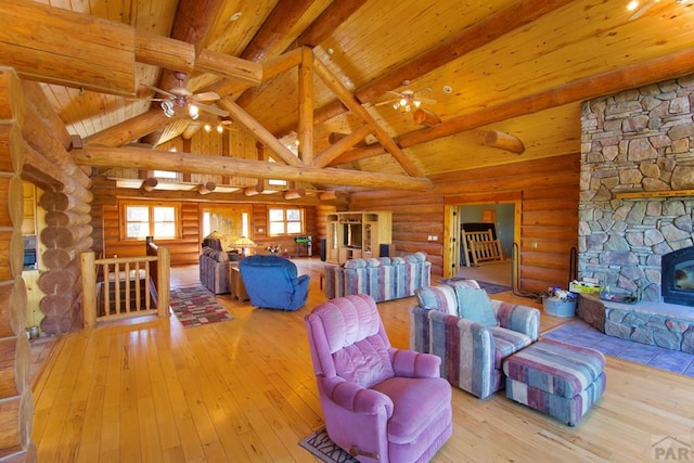 living area with hardwood / wood-style floors, a ceiling fan, wooden ceiling, vaulted ceiling with beams, and rustic walls