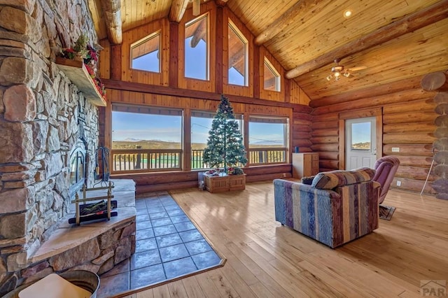 living room featuring beam ceiling, log walls, light wood-style floors, high vaulted ceiling, and wooden ceiling