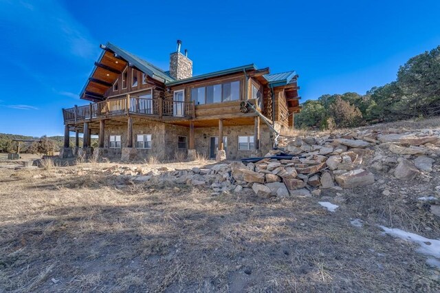 back of property with stone siding, a chimney, and a deck