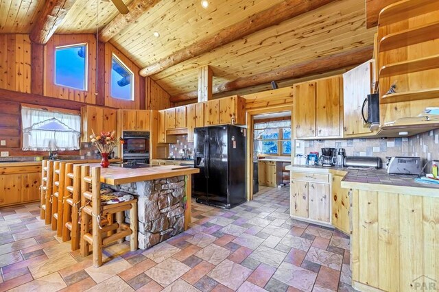 kitchen with wood ceiling, beam ceiling, black appliances, tasteful backsplash, and stone finish floor