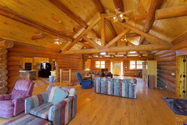 living room with beamed ceiling, ceiling fan, and rustic walls