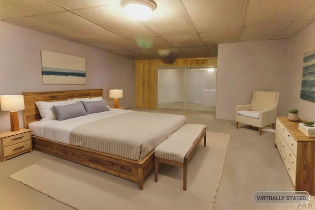 bedroom featuring light colored carpet, a drop ceiling, and a closet