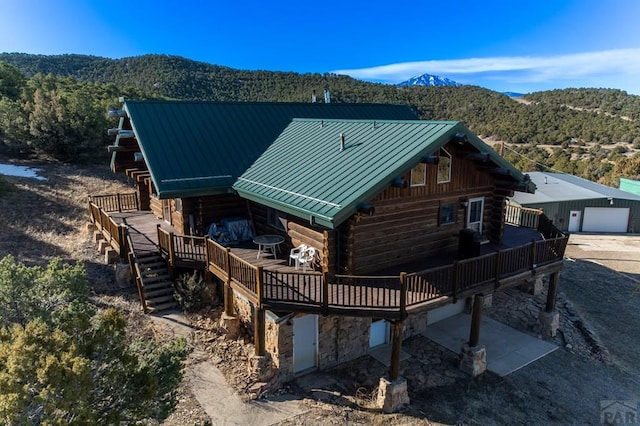 back of property with log siding, a deck with mountain view, a standing seam roof, stairs, and metal roof