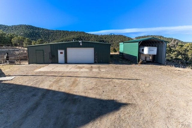 detached garage with a detached carport, driveway, and a mountain view