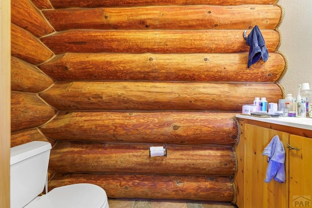 bathroom featuring vanity, rustic walls, and toilet