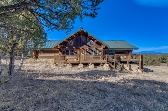 view of front facade featuring metal roof, a deck with mountain view, and log siding