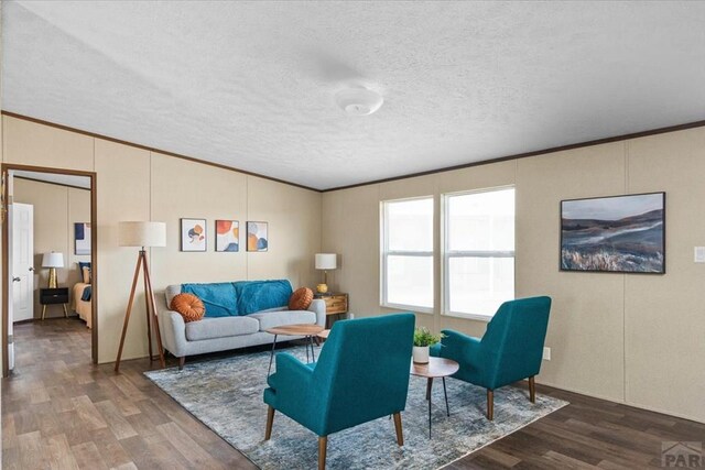 living area featuring vaulted ceiling, crown molding, and wood finished floors