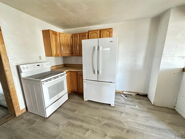 kitchen featuring white appliances, brown cabinets, and light wood finished floors