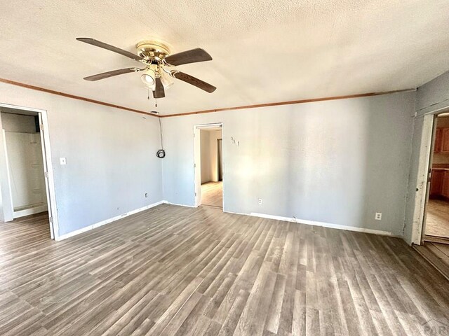 spare room featuring crown molding, a textured ceiling, baseboards, and wood finished floors