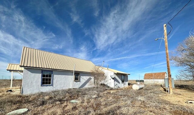 back of property featuring metal roof and stucco siding