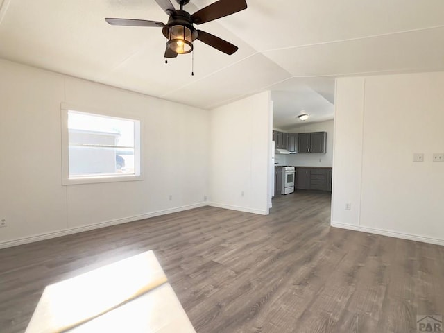 unfurnished living room with dark wood-type flooring, vaulted ceiling, baseboards, and ceiling fan