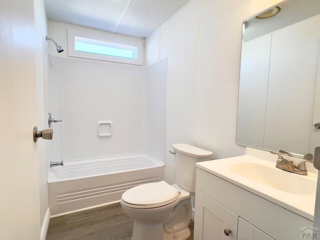 bathroom with bathtub / shower combination, toilet, a textured ceiling, vanity, and wood finished floors