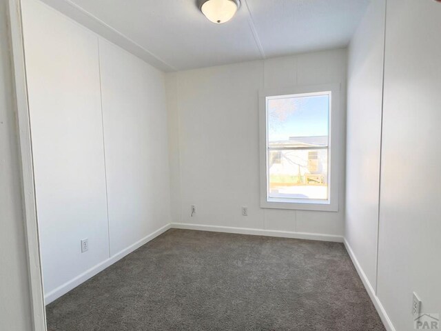 empty room featuring dark carpet and baseboards