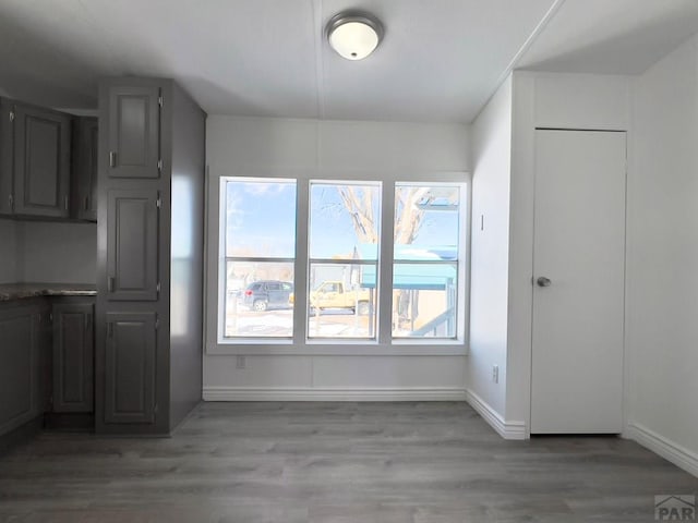 unfurnished dining area with light wood-style flooring and baseboards