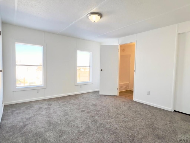 carpeted empty room with a textured ceiling, a wealth of natural light, and baseboards