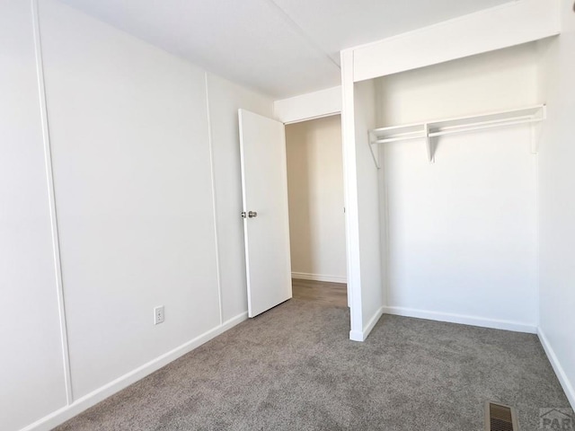 unfurnished bedroom featuring carpet floors, baseboards, visible vents, and a closet