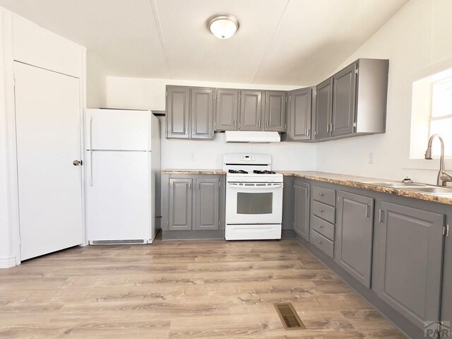 kitchen featuring under cabinet range hood, white appliances, a sink, visible vents, and gray cabinets