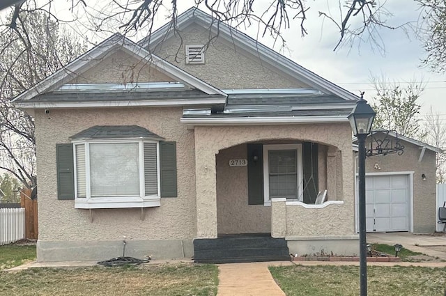 view of front facade with a porch, fence, an attached garage, and stucco siding