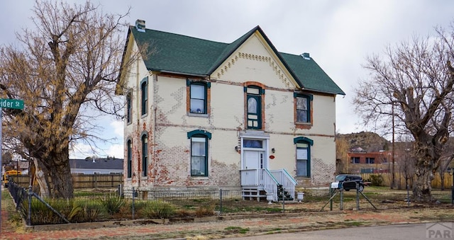 view of front of home featuring a fenced front yard, a chimney, and brick siding